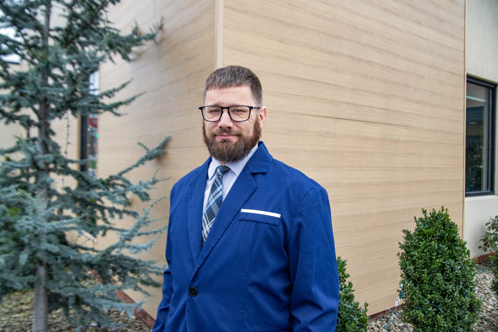 Zach Eddinger Portrait in front of some bushes and a building